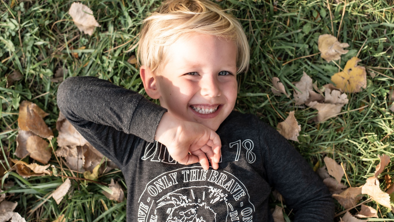 Улыбающийся маленький мальчик лежит на траве