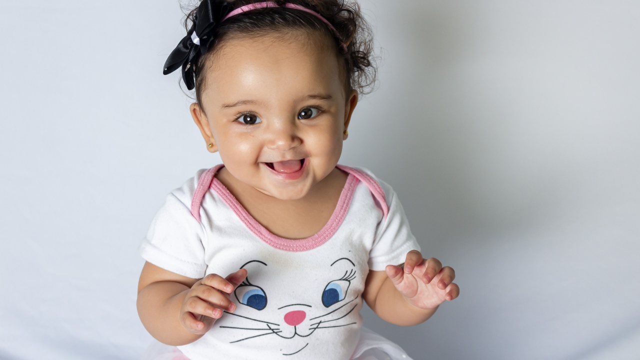 Улыбающаяся маленькая девочка на сером фоне 