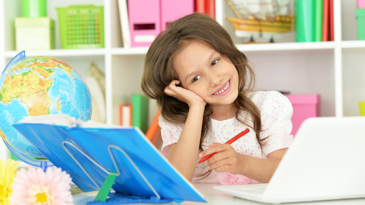 Улыбающаяся девочка ученица делает уроки 