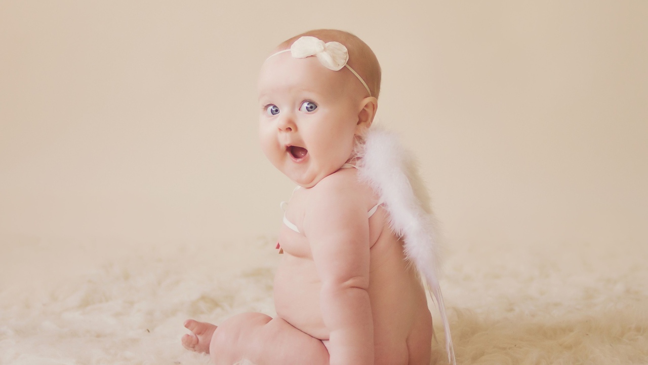Удивленный грудной ребенок с белыми крыльями за спиной 