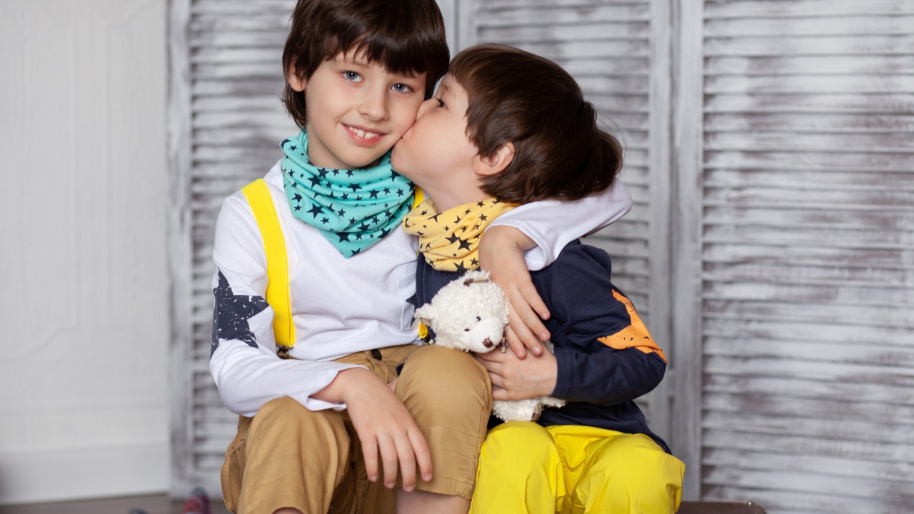 Два маленьких брата сидят на чемодане у стены