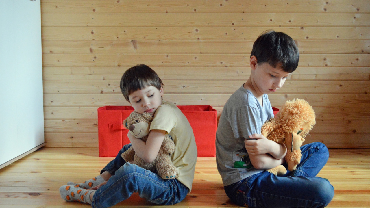 Два маленьких обиженных мальчика сидит на земле