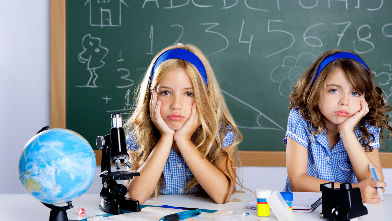 Две грустные девочка за партой в школе