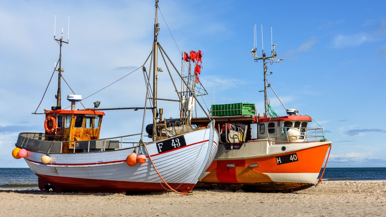 Две рыбацкие лодки стоят на песке у моря 