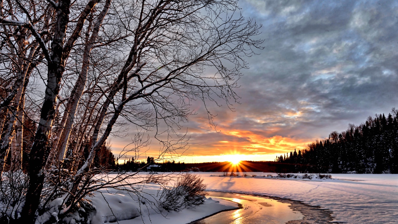 Покрытые снегом берега реки на рассвете зимнего солнца