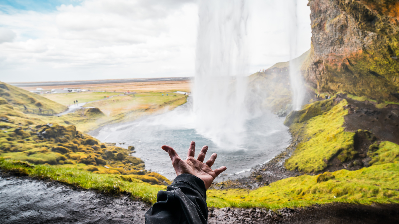 Рука тянется к водопаду Сельяландсфосс, Исландия