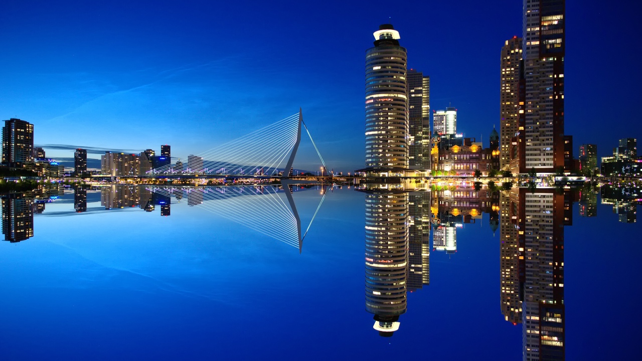 Небоскребы и мост отражаются в тихой воде
