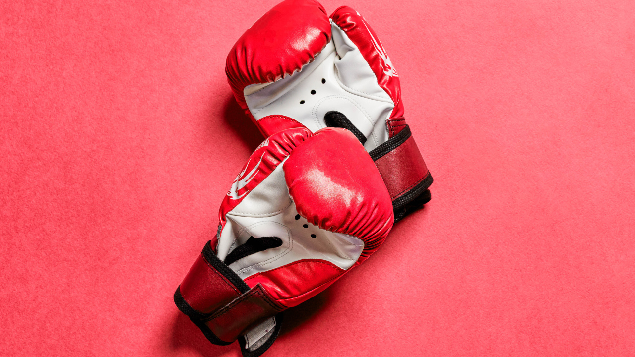 Красные боксерские перчатки на розовом фоне 