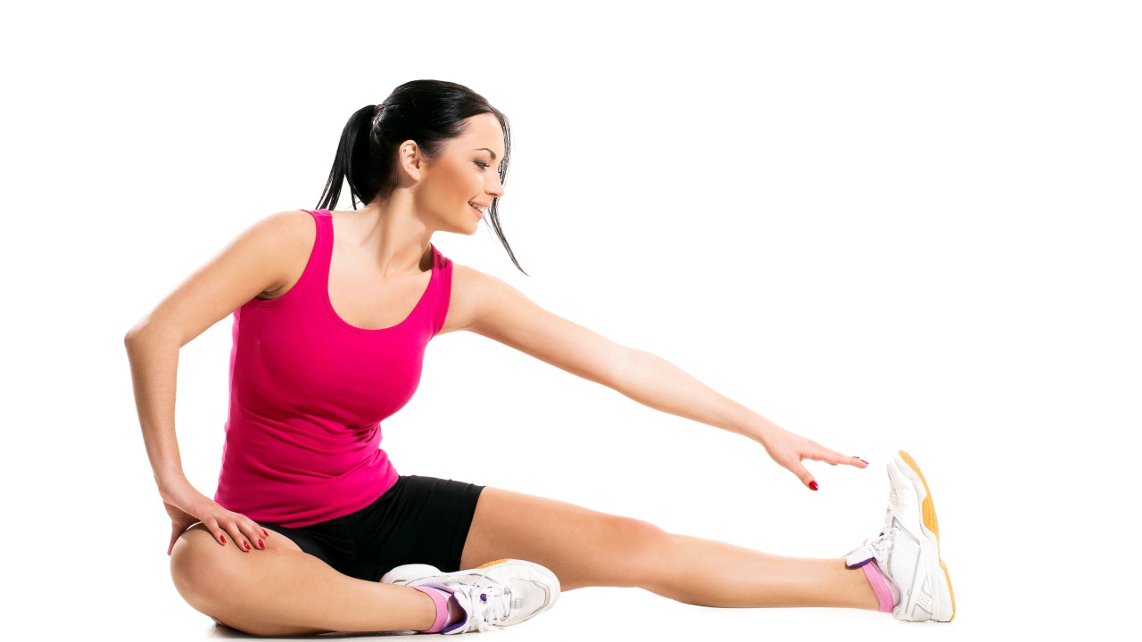 Спортивная девушка делает растяжку на белом фоне 