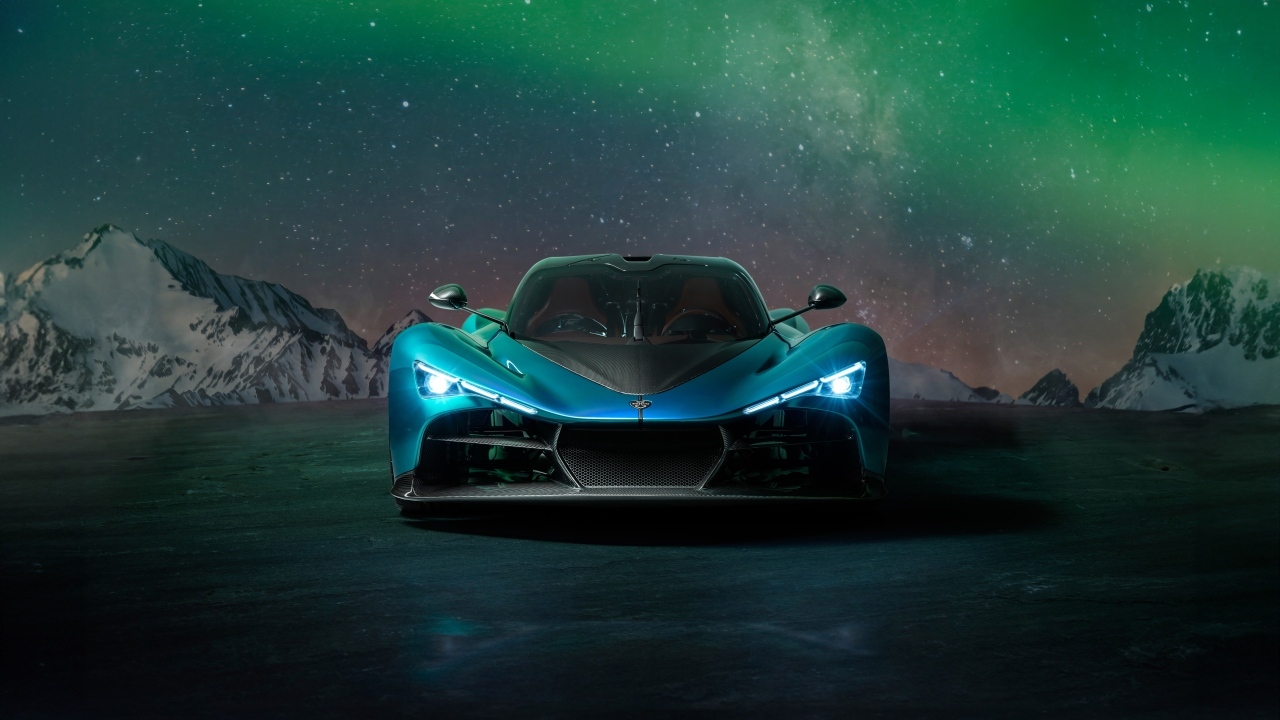 Голубой спортивный автомобиль Zenvo Aurora на фоне гор и полярного сияния