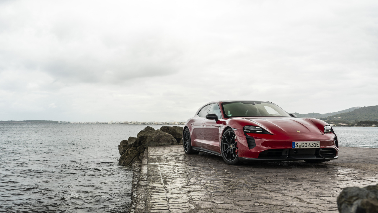 Красный автомобиль Porsche Taycan  у воды