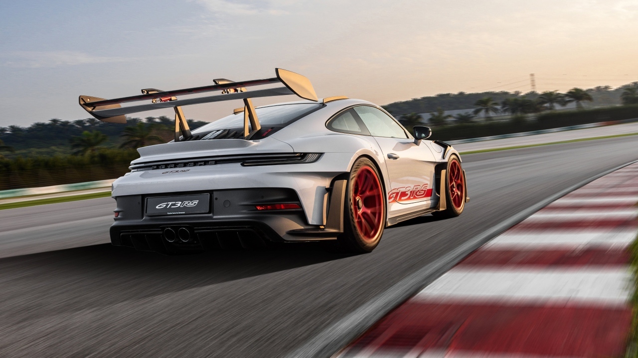 Серебристый спортивный автомобиль Porsche 911 GT3 RS Weissach Package 2023 года на трассе