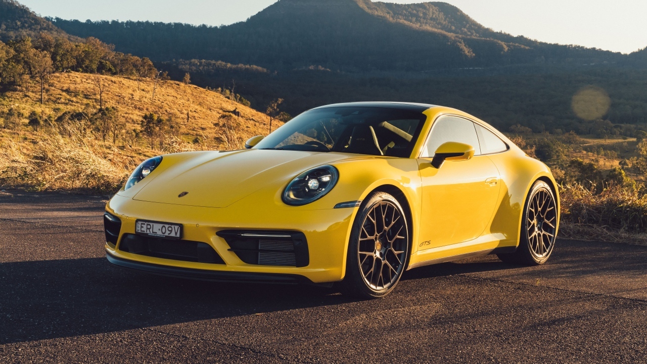 Желтый быстрый автомобиль Porsche 911 Carrera GTS вид спереди