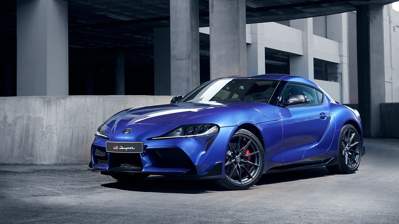 Синий автомобиль Toyota GR Supra 3.0 MT 2023 года у серого здания