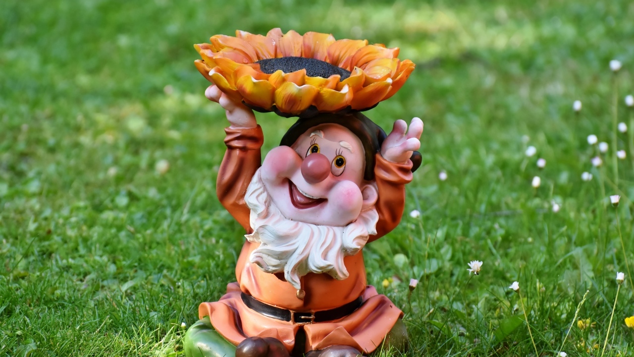 Садовая фигура гном за зеленой траве