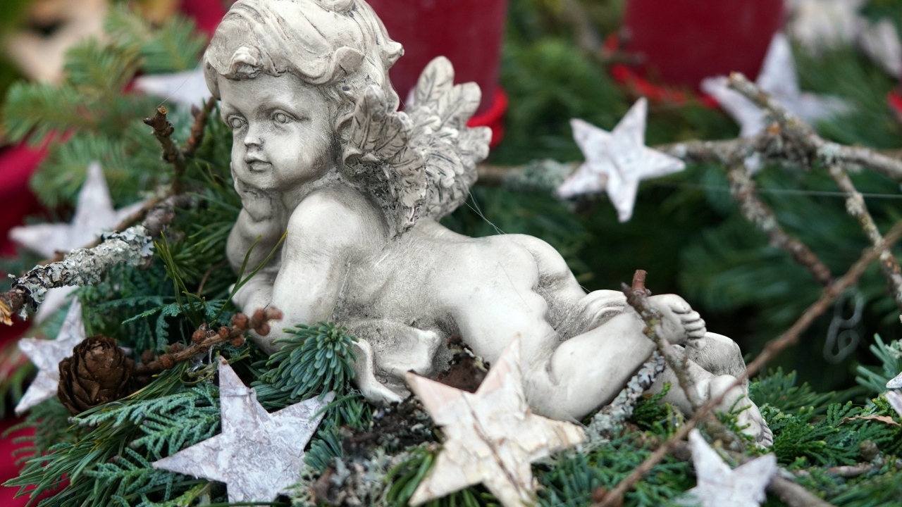 Статуэтка ангел лежит на ветках туи