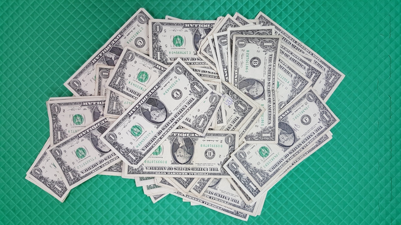 Много купюр в один доллар на зеленой поверхности