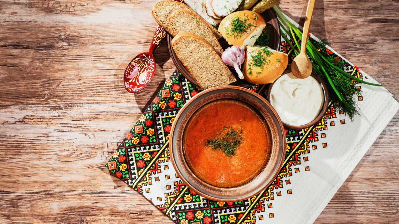 Тарелка борща на столе с салом, хлебом и зеленью