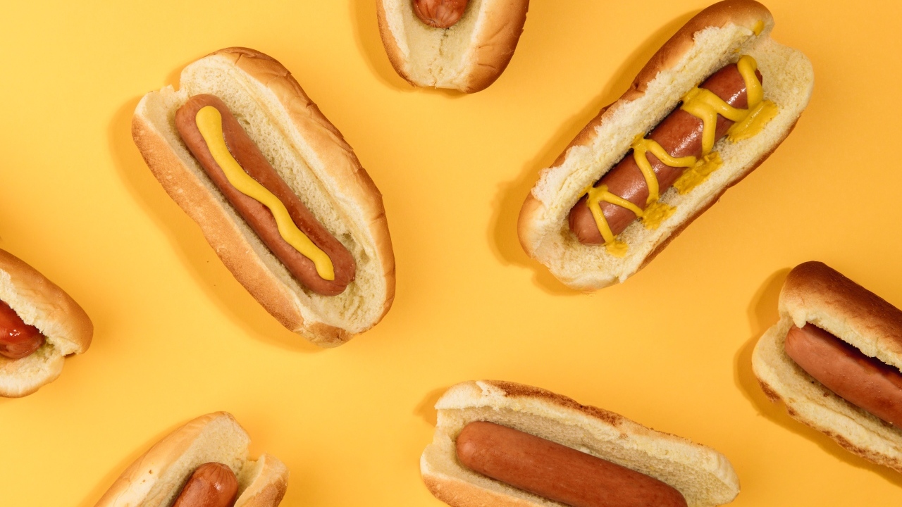 Аппетитные хот доги на желтом столе