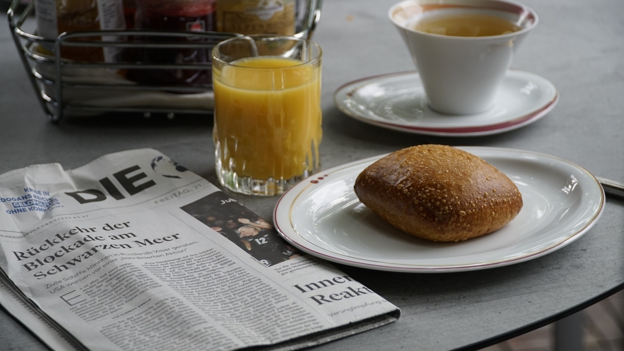 Булочка и стакан сока на столе с газетой