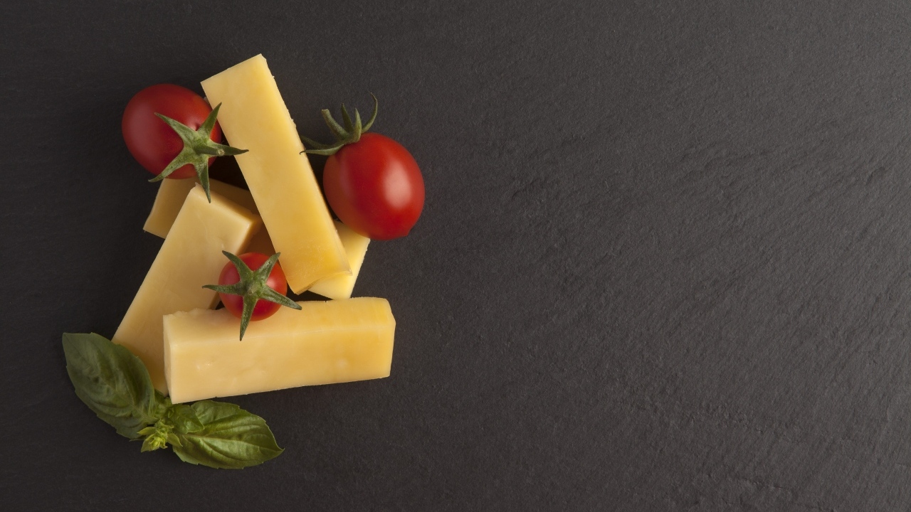 Сыр с помидорами и листьями базилика на сером столе