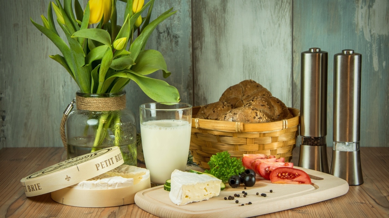 Сыр с овощами на столе с хлебом и букетом тюльпанов