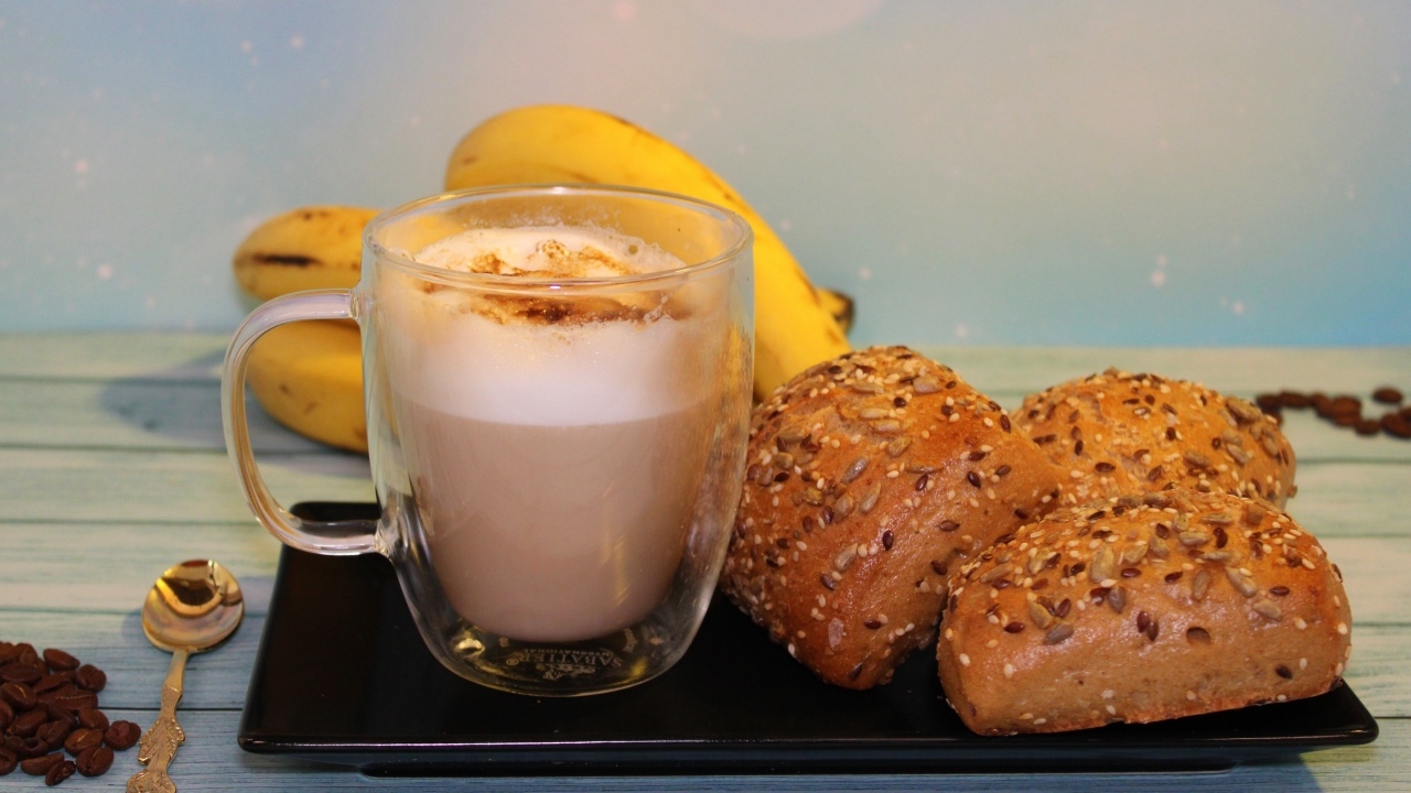 Чашка какао на столе с булочками и бананами