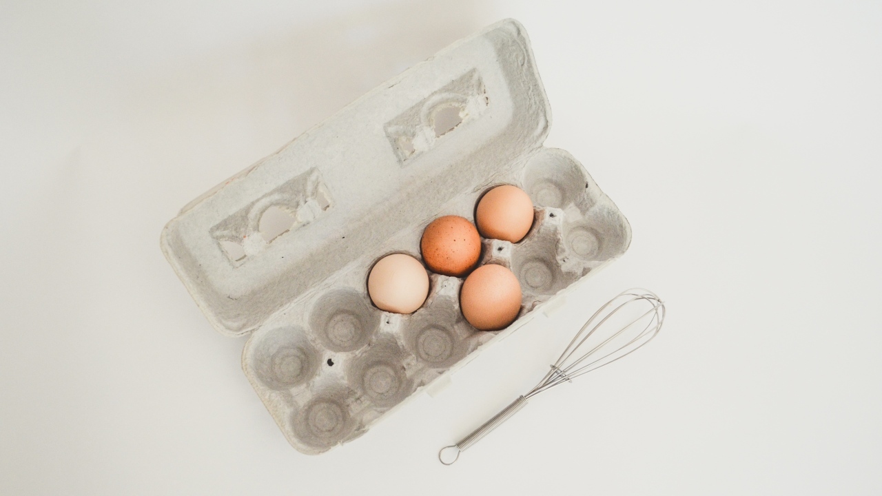 Четыре яйца в лотке на сером фоне