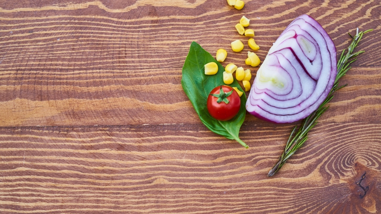 Половина лука на столе с кукурузой и помидором