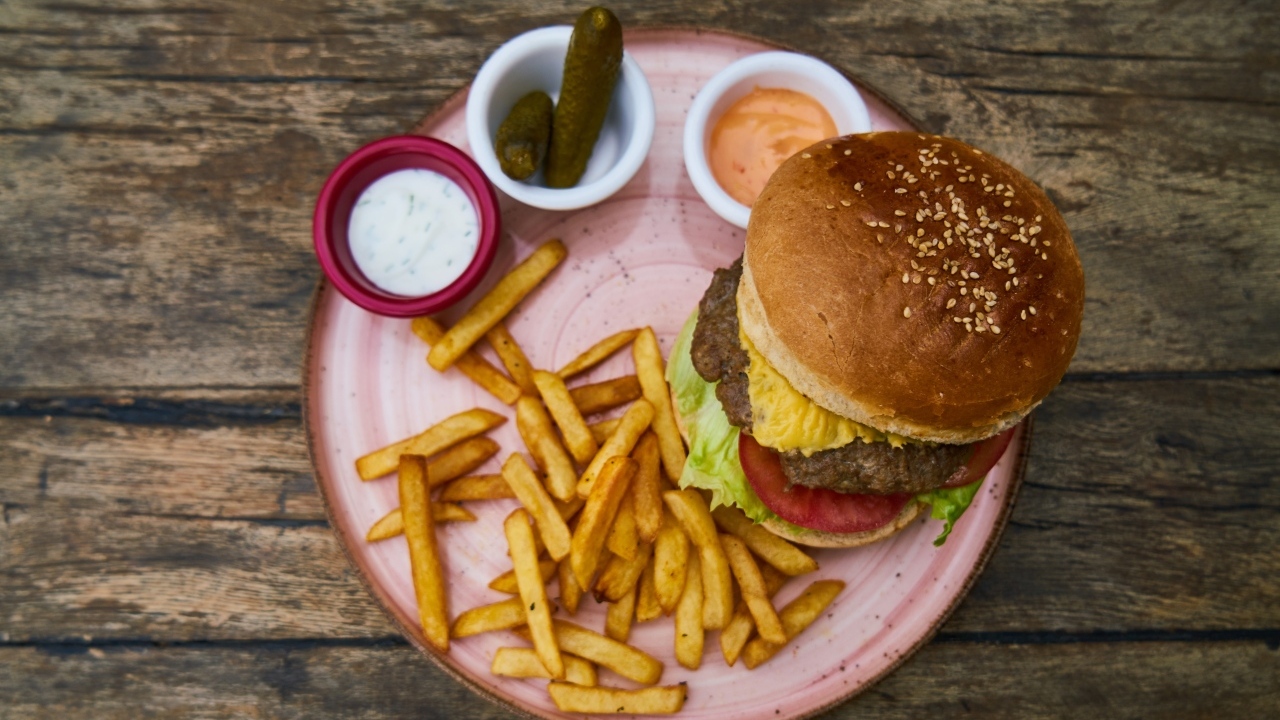 Гамбургер на тарелке с картофелем фри, огурцами и соусом