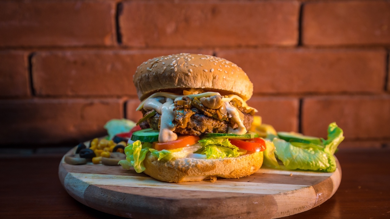 Большой аппетитный гамбургер на фоне стены