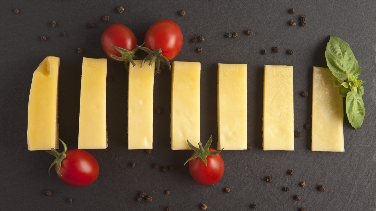Кусочки сыра с помидорами на сером столе