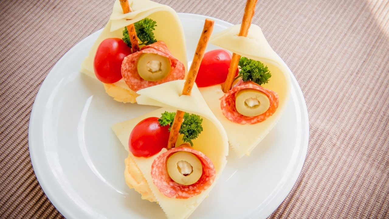 Бутерброды с колбасой, сыром и помидорами на белой тарелке