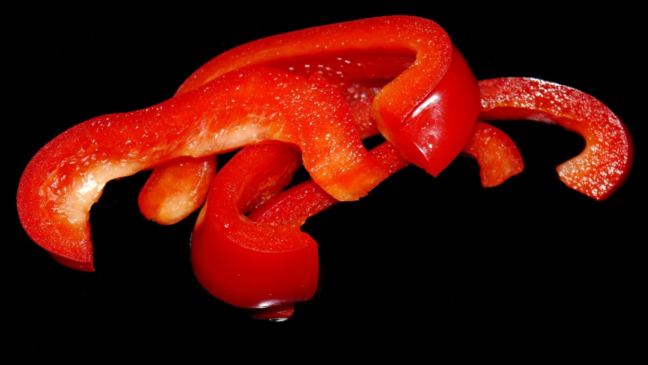 Нарезанный сладкий красный перец на черном фоне