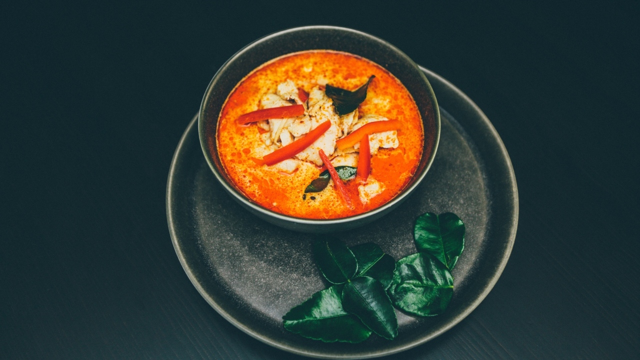 Острый суп в тарелке на черном фоне