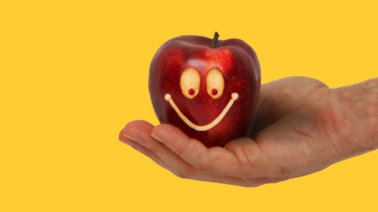Яблоко на ладони на желтом фоне