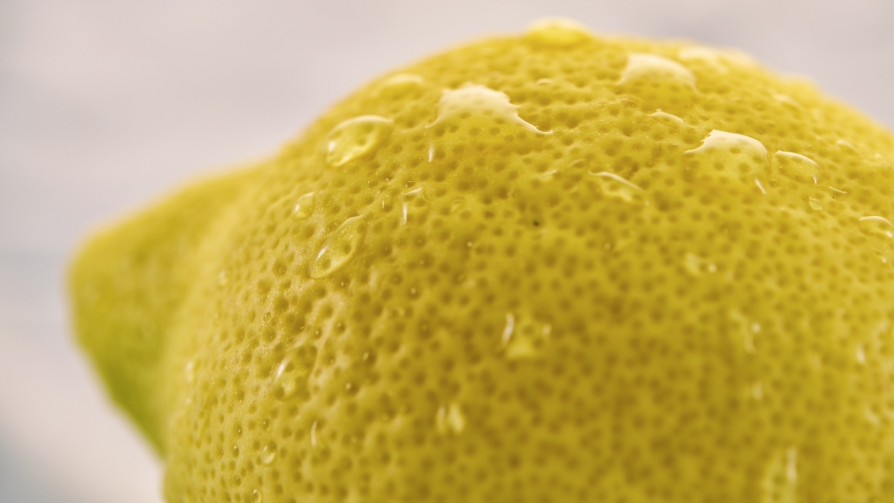 Большой желтый лимон в каплях воды крупным планом
