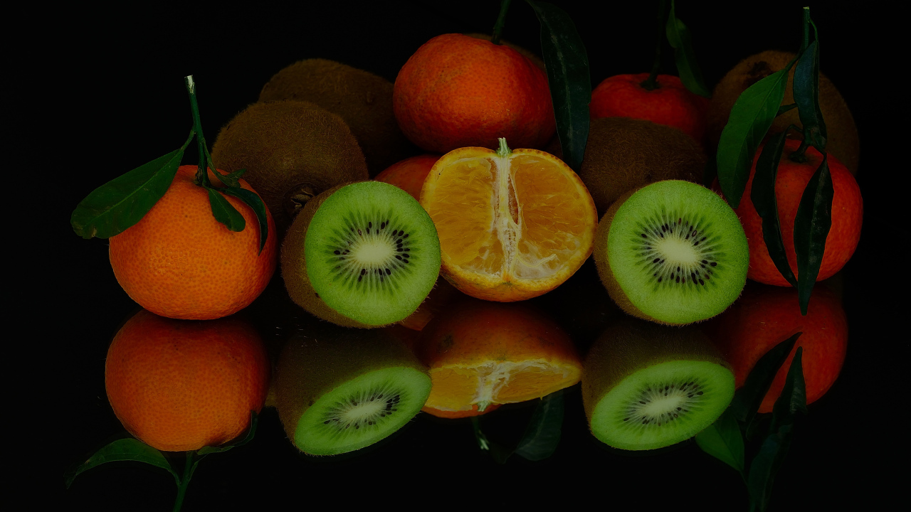 Цитрусовые фрукты на черной зеркальной поверхности