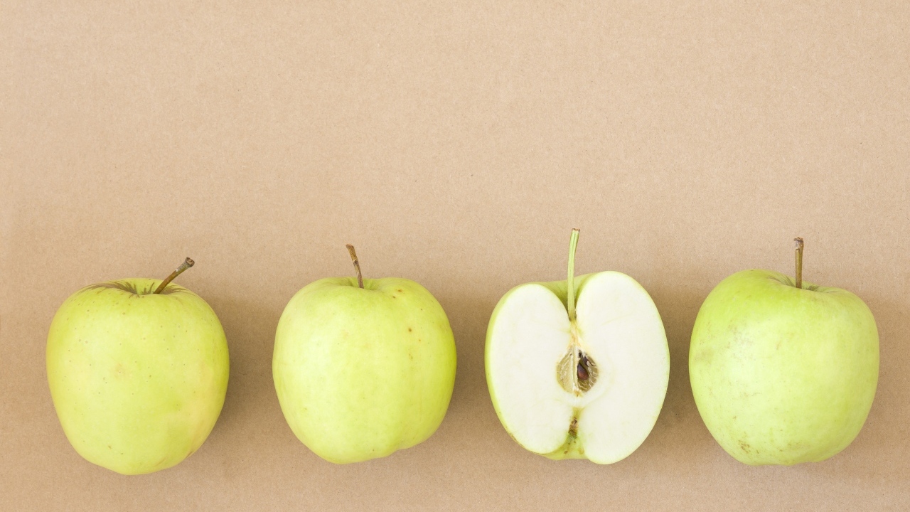 Четыре зеленых яблока на бежевом фоне 