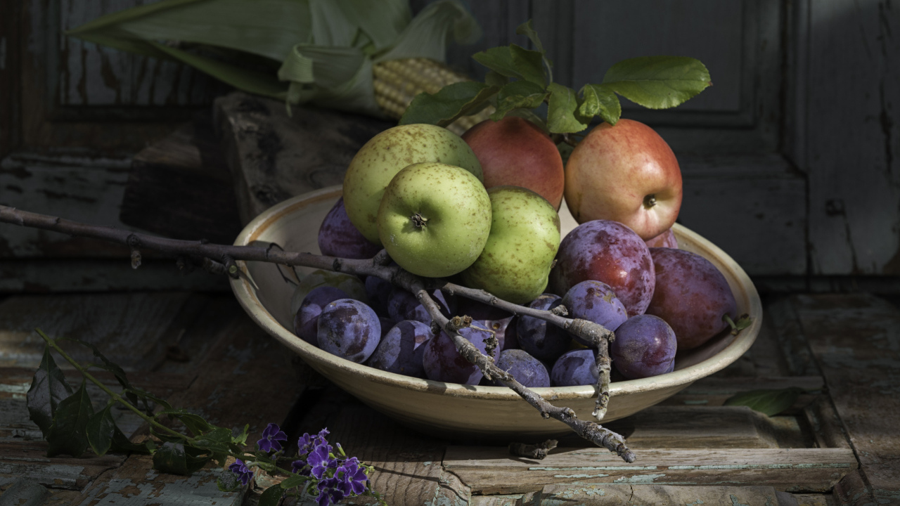 Спелые сливы на тарелке с яблоками