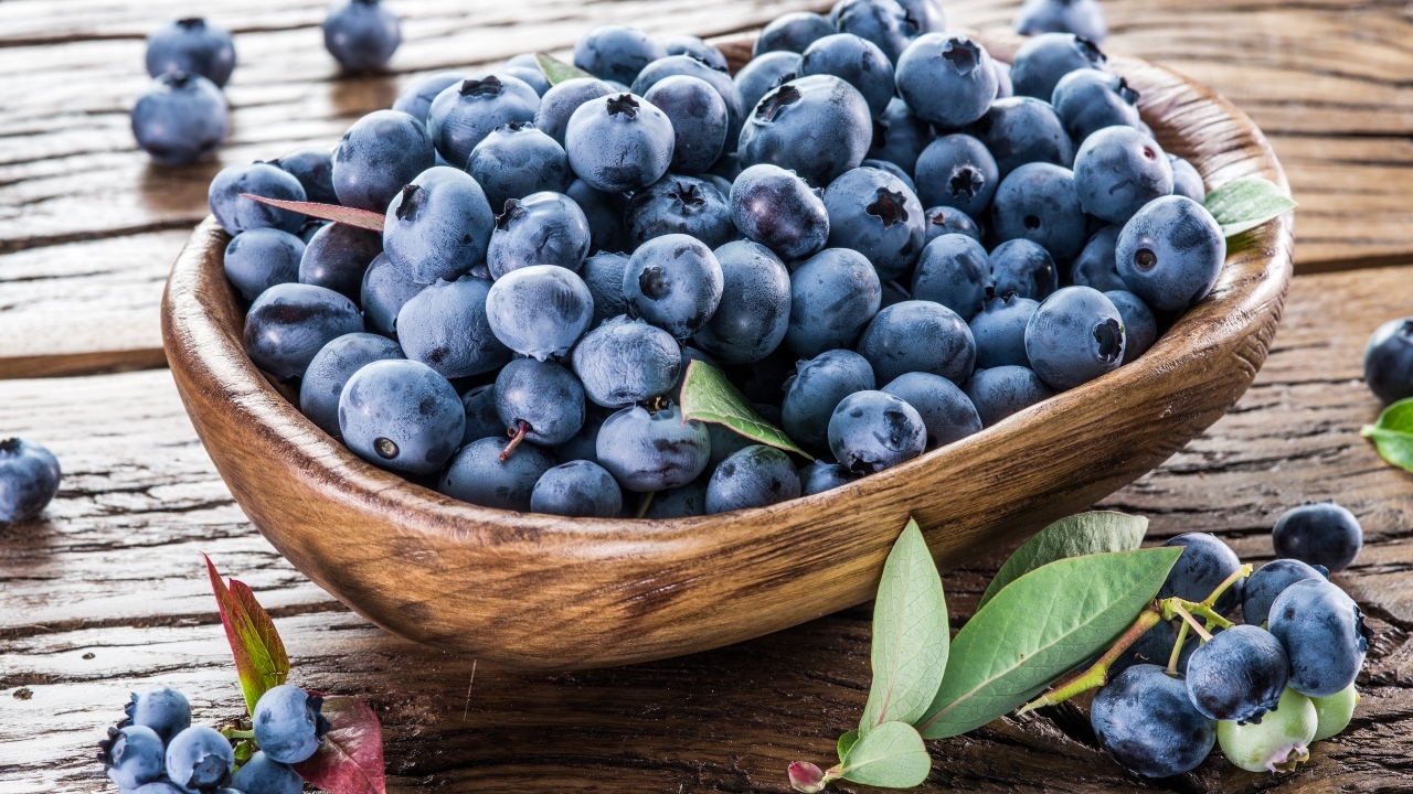 Деревянная тарелка с ягодами черники на столе