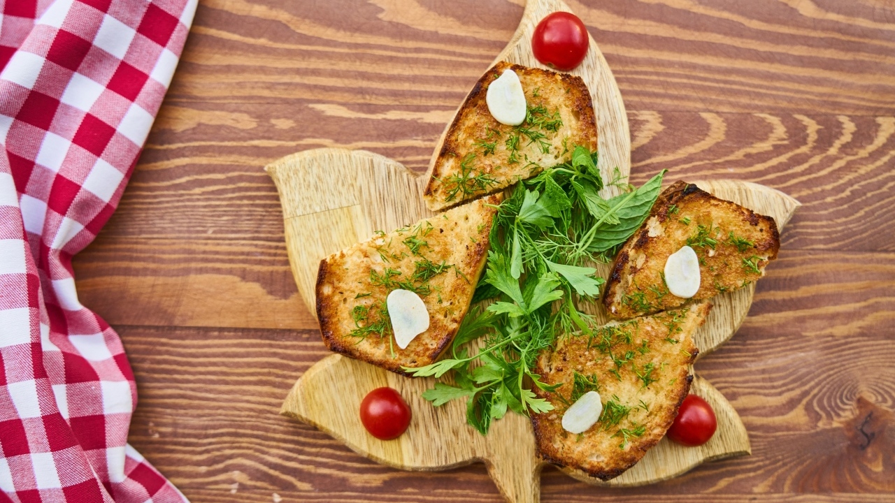 Жареный хлеб на доске с зеленью и помидорами