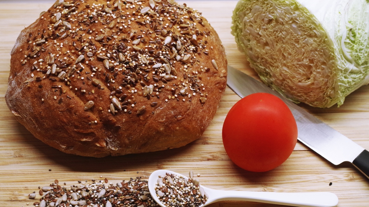 Буханка хлеба на столе с капустой и помидором