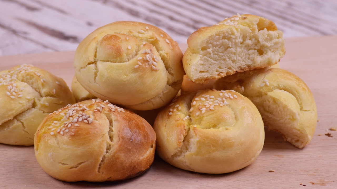 Аппетитные сладкие булочки с кунжутом на столе