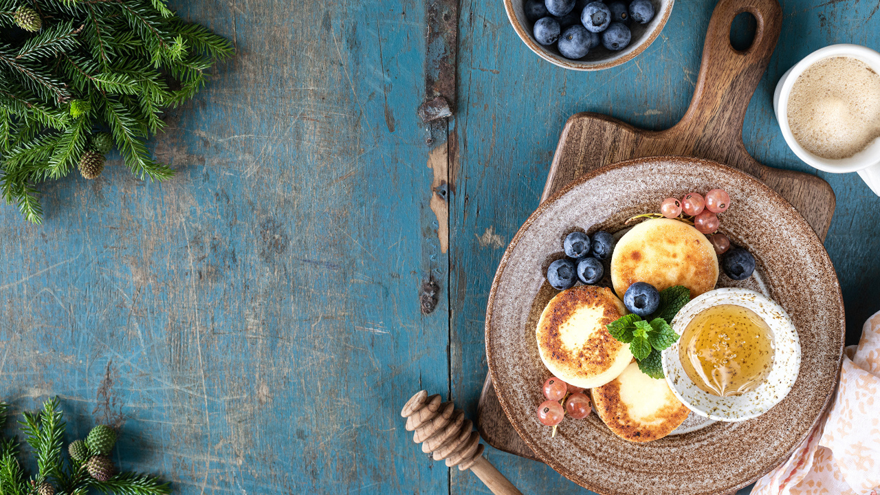 Сырники с ягодами черники на тарелке с медом