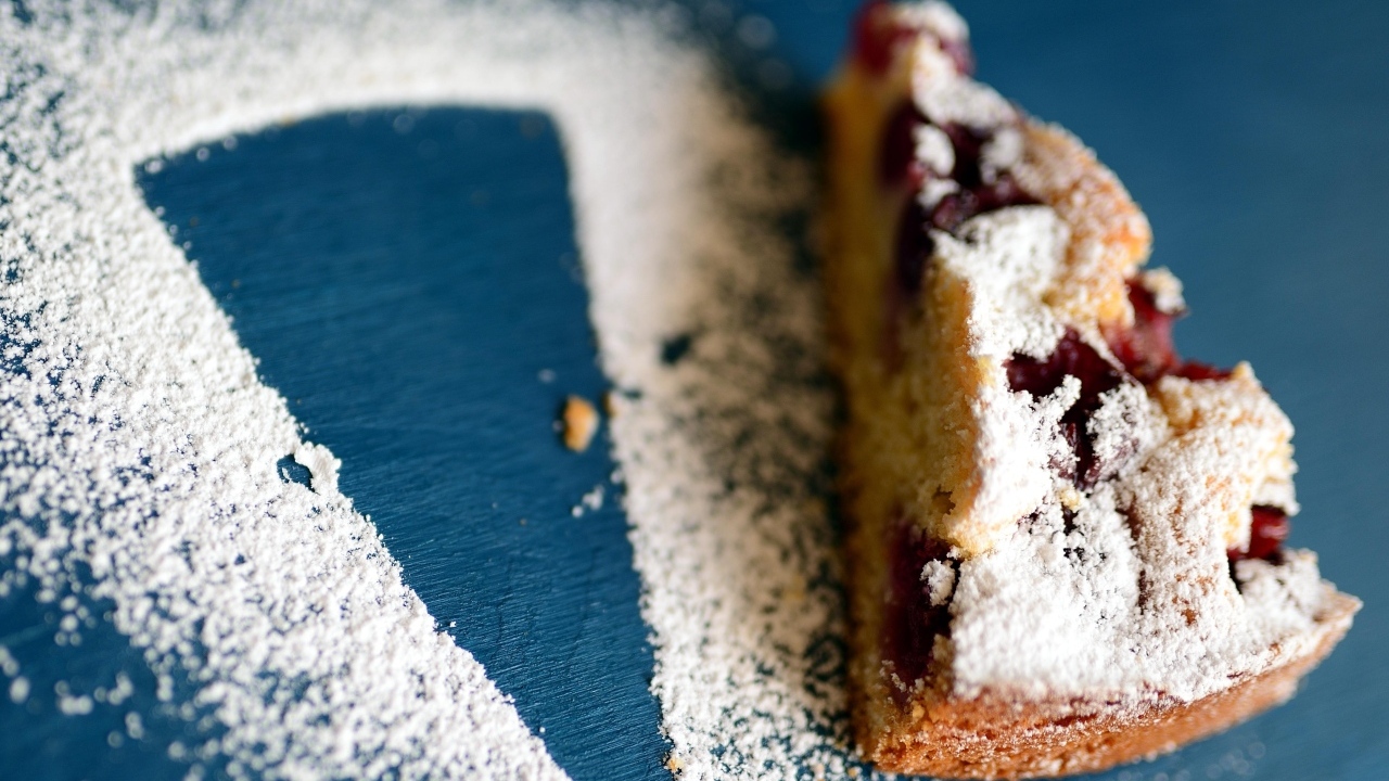 Кусок пирога с ягодами на столе с сахарной пудрой