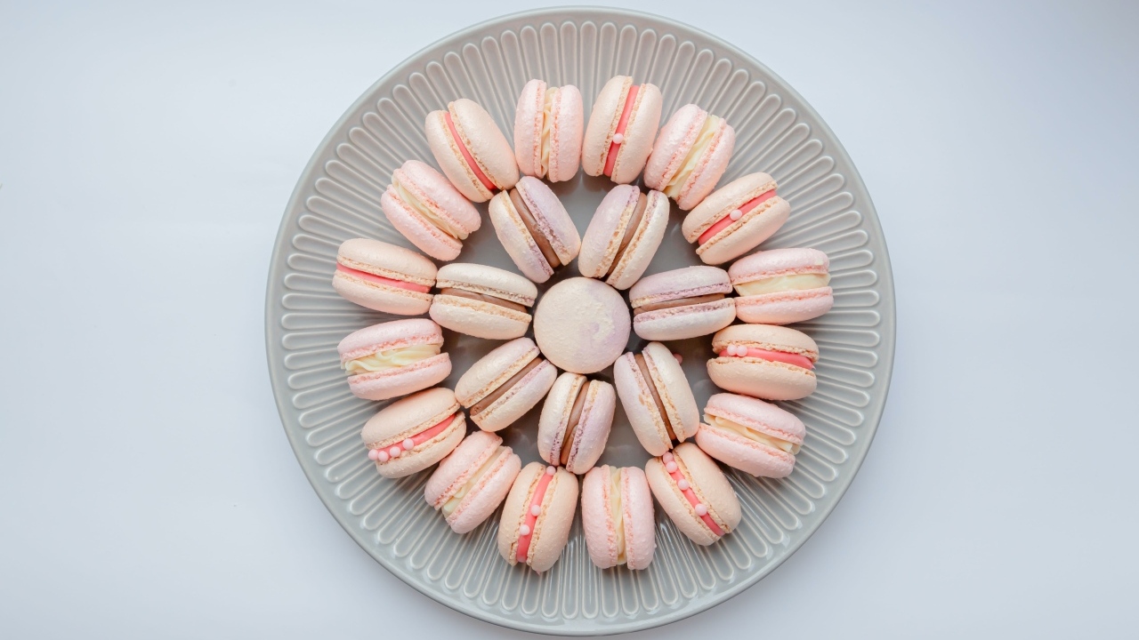 Розовый десерт макарон на большой тарелке