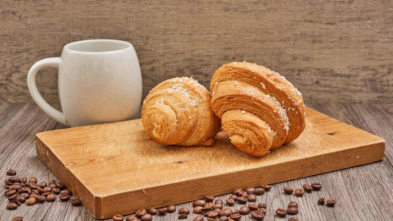 Два круассана на доске с кофейными зернами
