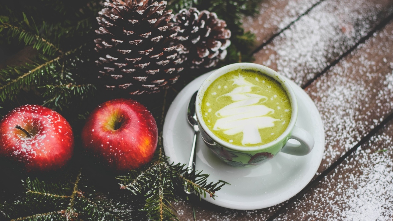 Чашка кофе на столе с яблоками и шишками