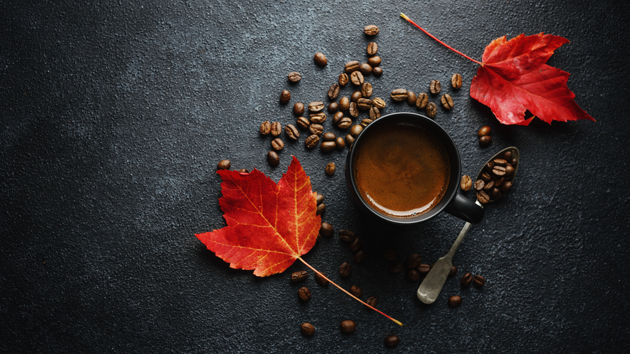 Чашка кофе на столе с зернами и желтыми листьями
